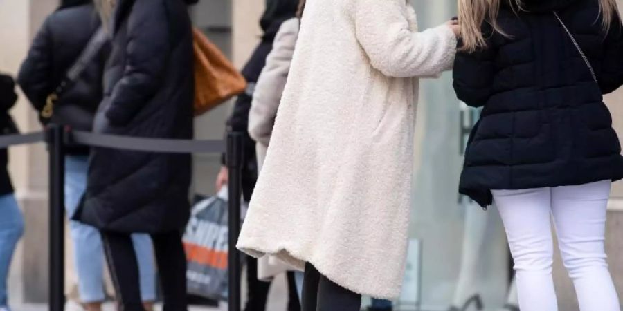 Menschen warten vor einem Geschäft in der Münchner Innenstadt auf Einlass. Die Wirtschaft reagiert erleichtert auf die Absage des Oster-Lockdowns. Foto: Sven Hoppe/dpa