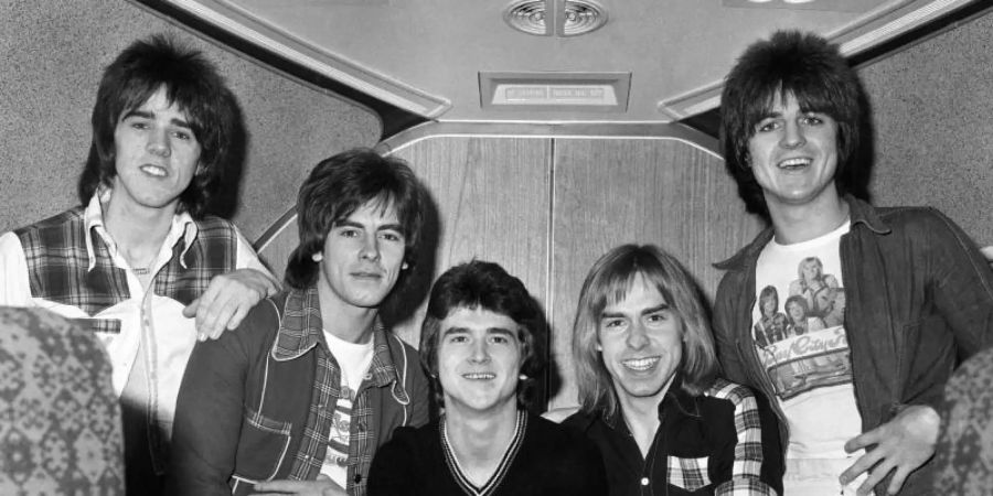 Stuart Wood (l-r), Alan Longmuir, Leslie Mckeown, Derek Longmuir und Eric Faulkner warten in einem Jumbo-Jet auf dem Londoner Flughafen Heathrow auf den Abflug zu einer Tournee durch Australien (1975). Foto: Pa/PA Wire/dpa