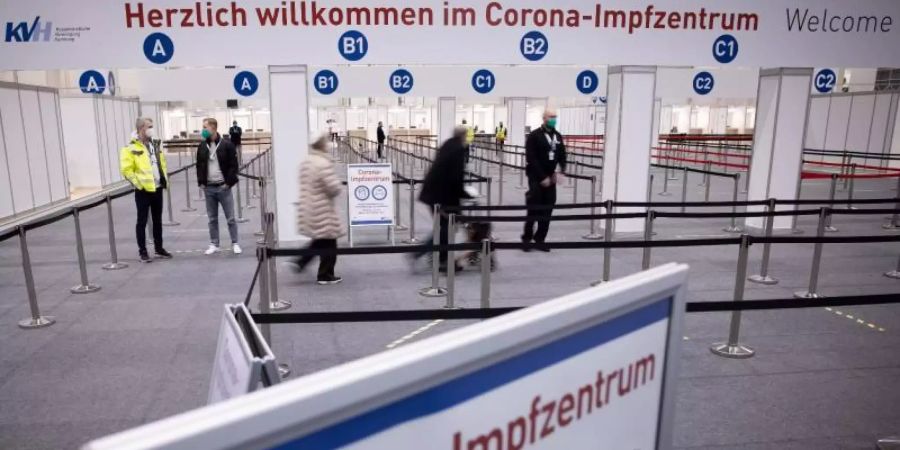 Zwei Senioren (M) sind im Eingangsbereich des Corona-Impfzentrums in den Hamburger Messehallen auf dem Weg zur Impfung. Foto: Christian Charisius/dpa