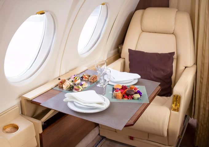 Die Passagieren lassen es sich im Privatjet gut gehen (Themenbild). Travelcoup Privatjet Essen