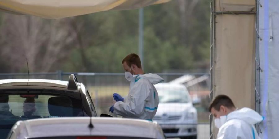 Mitarbeiter der Johanniter-Unfall-Hilfe e.V. testen in einem Zelt des «Drive in»-Corona-Test in Oranienburg die Insassen zweier Autos auf Corona. Foto: Soeren Stache/dpa