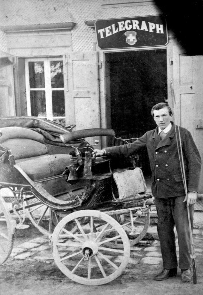 Der letzte Kondukteur der Gotthard-Postkutsche Isidoro Christen posiert vor einer Schweizer Telegrafen-Poststelle an der Gotthard-Route. Postkutsche Gotthard