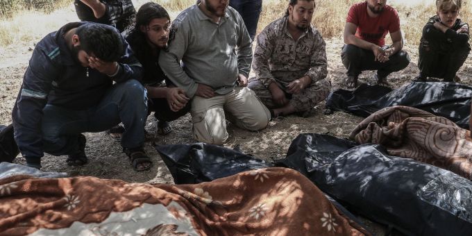 Trauernde sitzen 2021 neben eingehüllten Leichen unter Bäumen in Idlib und warten darauf, dass Kampfflugzeuge abziehen. Trauernde sitzen 2021 neben eingehüllten Leichen unter Bäumen in Idlib und warten darauf, dass Kampfflugzeuge abziehen.