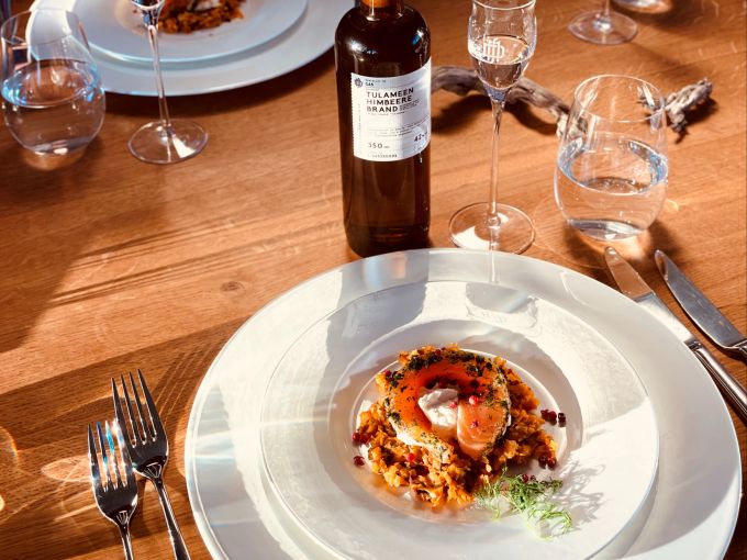 Zum mit Mandarinen- oder Dillgeist gebeizten Lachs von Tim Müller passen als Getränke ein Zitrus- oder Gurkengeist, aber auch ein Himbeerbrand. Teller Lachs Gericht Besteck Flasche