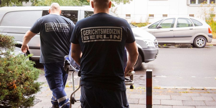Mitarbeiter der Gerichtsmedizin holen eine Leiche aus einer Wohnung eines Mehrfamilienhauses in Berlin.