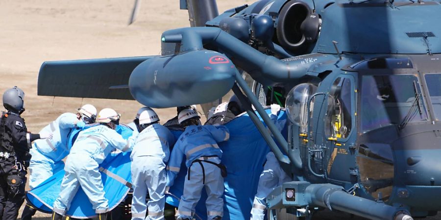 Rettungskräfte transportieren eine gerettete Person aus einem Hubschrauber auf der Insel Hokkaido. Foto: Koki Sengoku/Kyodo News/AP/dpa