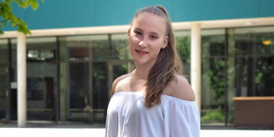 Niedersachsens jüngste Abiturientin Mandy Hoffmann steht mit Blumen in der Hand vor ihrer Schule. Mandy hat mit 14 Jahren das Abitur mit der Note 1,0 bestanden. Foto: Katrin Hoffmann