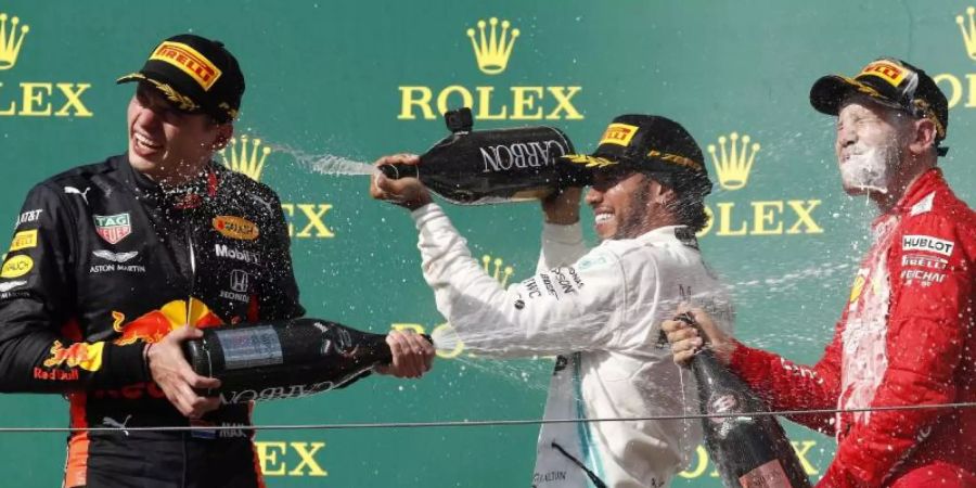 Champagnerdusche: Sieger Lewis Hamilton (M) mit Max Verstappen (l) und Sebastian Vettel auf dem Podium in Budapest. Foto: Laszlo Balogh/AP