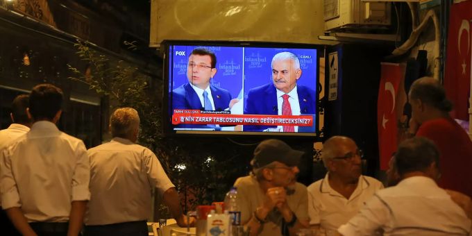 Menschen sehen eine Liveübertragung einer Fernsehdebatte zwischen den Bürgermeisterkandidaten für Istanbul, Binali Yildirim (r) und Ekrem Imamoglu (l). Kommunalwahlen in der Türkei