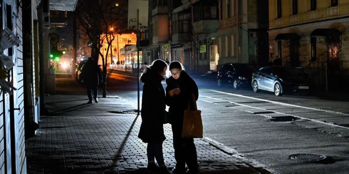 Frauen nutzen ein Smartphone an einer Bushaltestelle in der ukrainischen Hauptstadt Kiew. Kiew