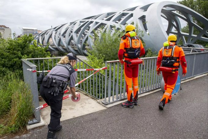 Eine Polizistin sperrt die Unterführung der Hans-Wilsdorf-Brücke, nachdem die Feuerwehr am Ufer der Arve die Brücke nach starkem Regen in der Nacht zum Dienstag, 13. Juli 2021, in Genf kontrolliert hat. hochwasser