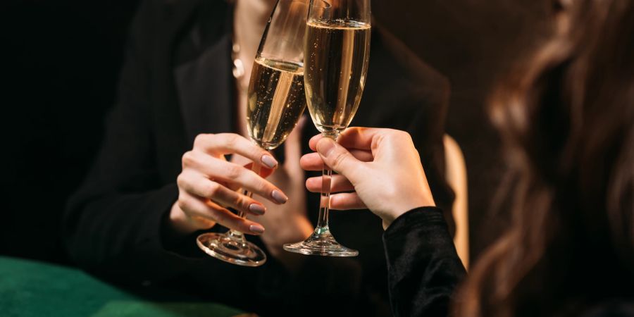 Zwei Frauen stossen mit Champagner Gläsern am Casino Spieltisch an.