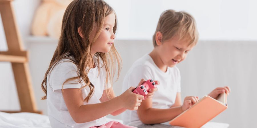 zwei Kinder spielen, lesen