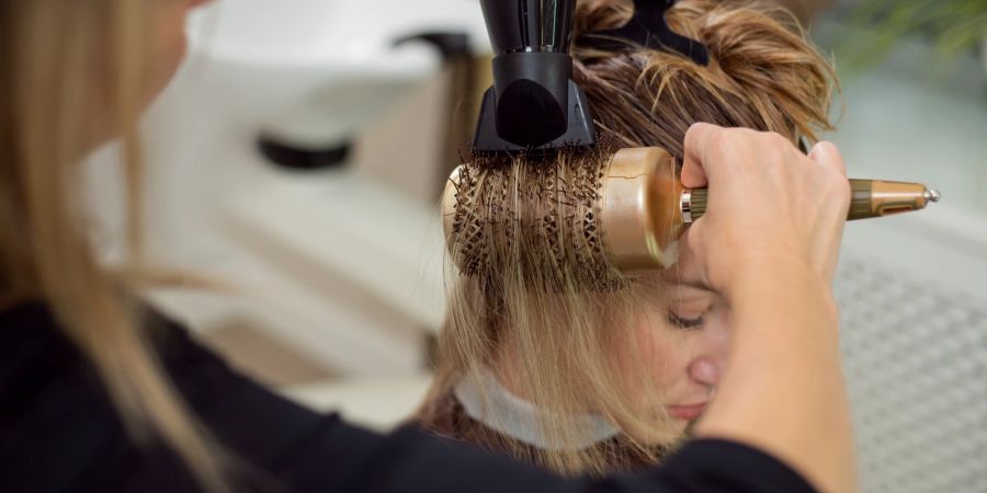 Frau werden die bloneden Haare geföhnt.