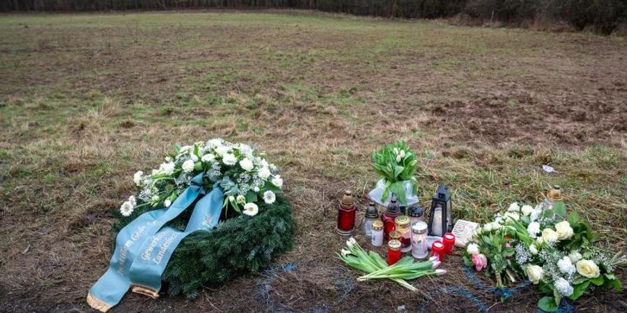 Ein Kranz sowie Blumen und Kerzen liegen am Tatort in Rheinland-Pfalz, wo zwei junge Polizisten getötet wurden. Foto: Harald Tittel/dpa