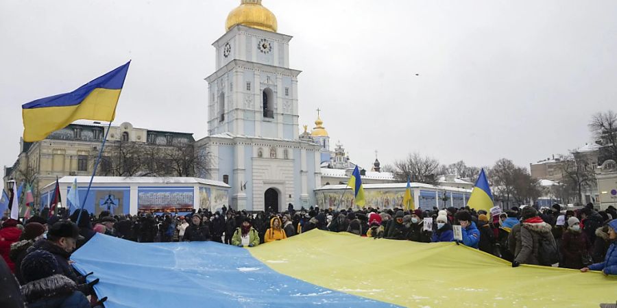 Aktivisten Aktivisten zeigen eine riesige ukrainische Nationalflagge während einer «Say-NO-to-Putin»-Kundgebung in der Nähe der St. Michael-Kathedrale. Foto: Efrem Lukatsky/AP/dpa