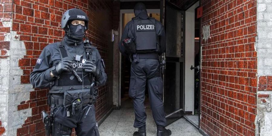 Polizisten stehen in einem Hauseingang im Stadtteil Laar. Foto: Christoph Reichwein/dpa