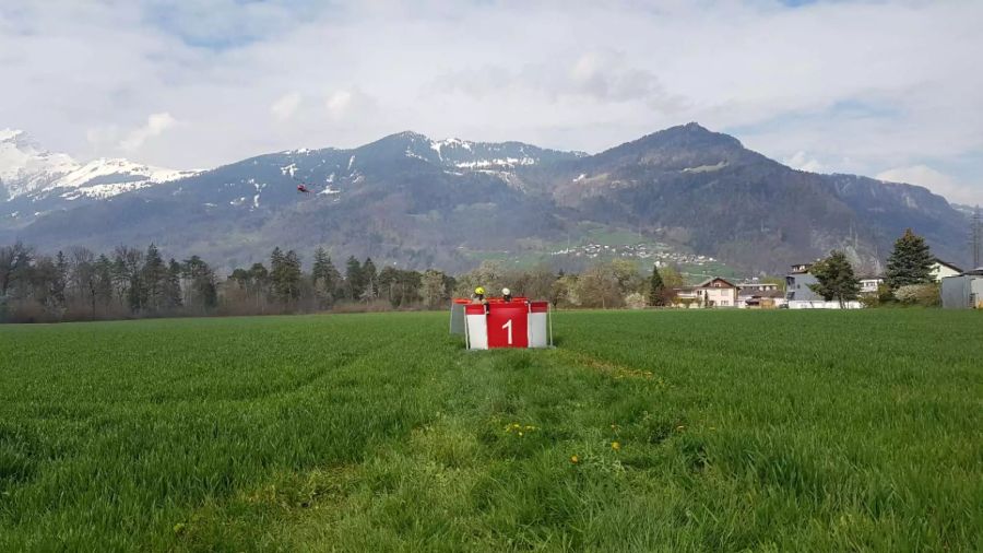 Das Wasserentnahmebecken auf dem Boden und der Helikopter der angeflogen kommt.