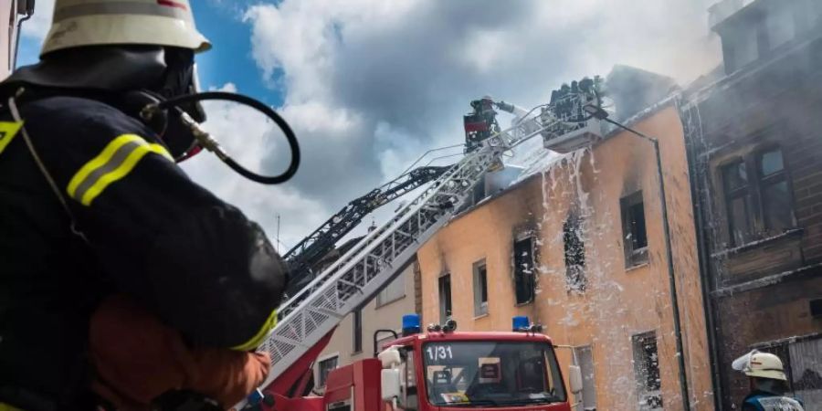 Einsatzkräfte der Feuerwehr löschen den Brand in dem Mehrfamilienhaus in Neunkirchen. Foto: Oliver Dietze