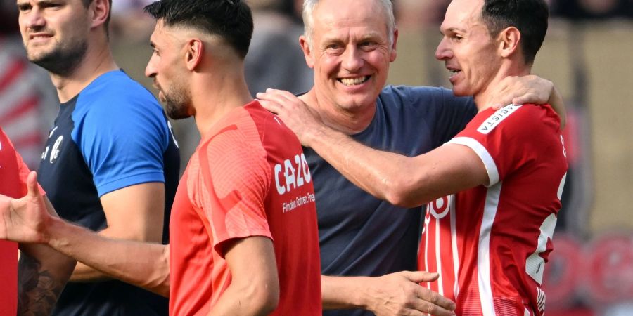 Freiburgs Trainer Christian Streich (l) freut sich mit seinen Spielern nach dem Sieg in Leverkusen.