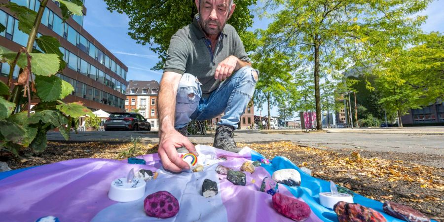 Felix Adrian Schäper vom Verein  Trans*Inter*-Münster vor einer Fahne mit Gedenksteinen in Münster.