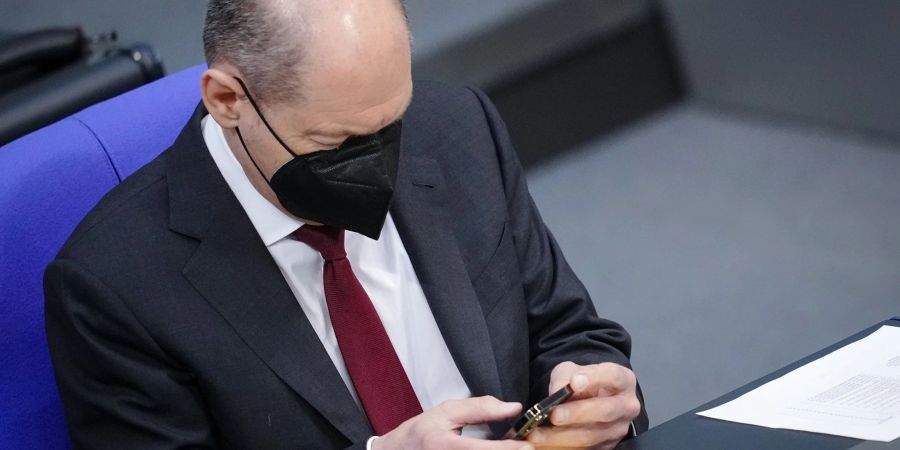 Bundeskanzler Olaf Scholz schaut im Bundestag auf sein Handy (Archivbild).