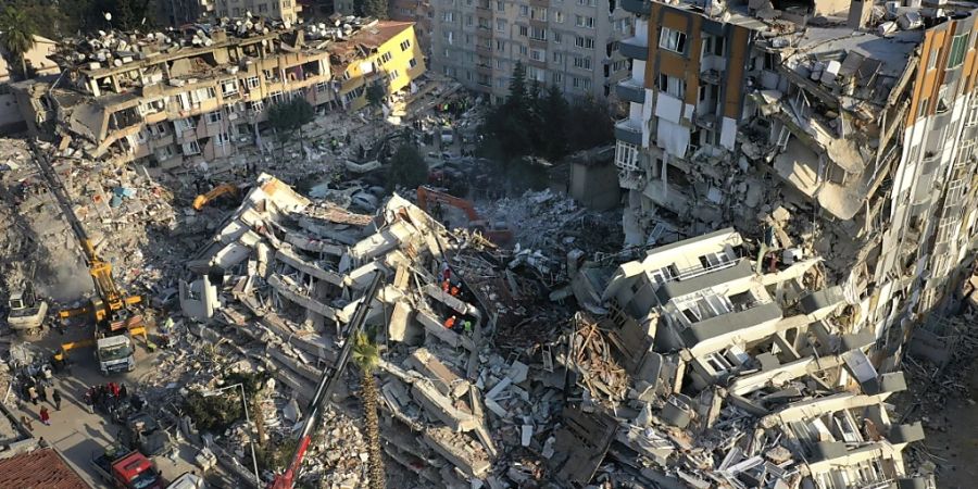 Rettungsteams suchen nach Menschen, während Kräne Trümmer von zerstörten Gebäuden entfernen. Foto: Hussein Malla/AP/dpa