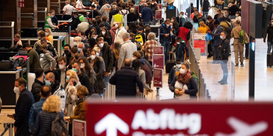 Zahlreiche Fluggäste warten im Terminal 1 des Flughafens BER in einer Schlange auf die Sicherheitskontrolle.