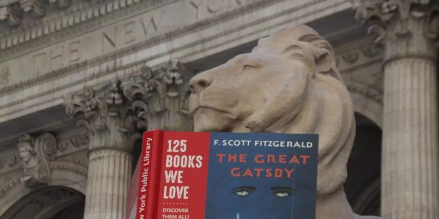 Der Löwe «Fortitude» vor der New York Public Library liest den «Grossen Gatsby». Foto: Christina Horsten/dpa