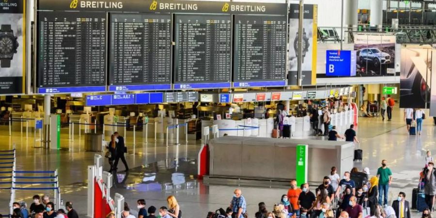 Reisende stehen in der Abflughalle im Terminal 1 am Flughafen Frankfurt. Hier herrscht noch immer deutlich weniger Betrieb als in Vor-Corona-Zeiten. Foto: Andreas Arnold/dpa