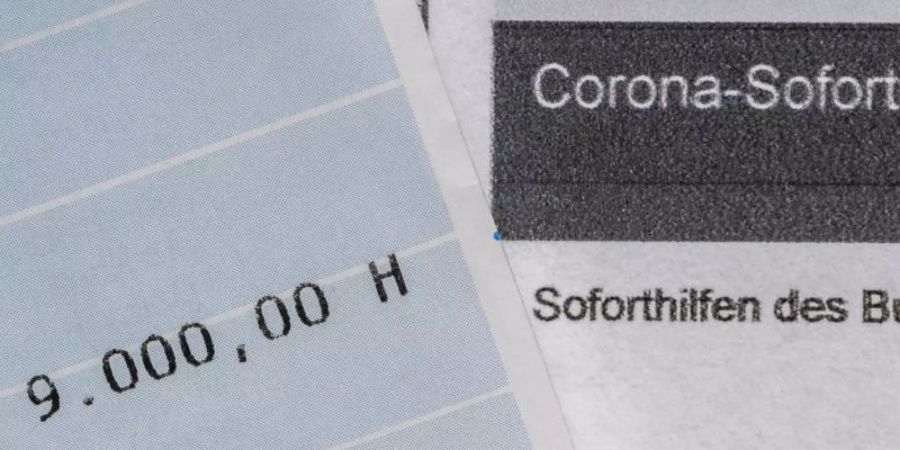 Ein Kontoauszug mit der überwiesenen Summe von 9.000 Euro Corona-Soforthilfe liegt auf einem Antrag für den Zuschuss der Sächsischen Aufbaubank. Foto: Robert Michael/dpa-Zentralbild/dpa