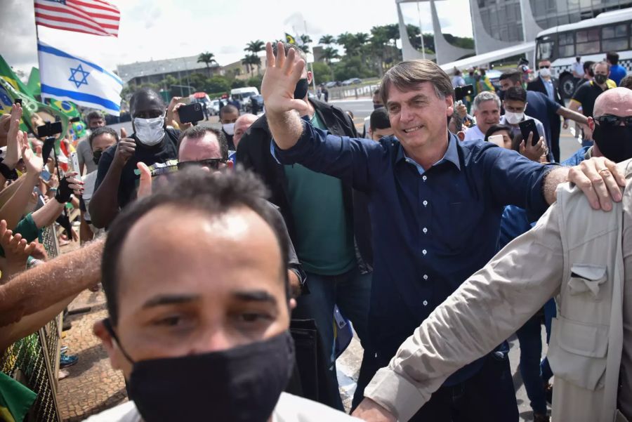 Jair Bolsonaro (r), Präsident von Brasilien, winkt inmitten der Corona-Pandemie Anhängern zu.