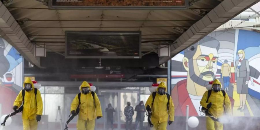 Städtische Angestellte desinfizieren einen Bahnhof in Moskau. Foto: Alexander Zemlianichenko Jr/XinHua/dpa