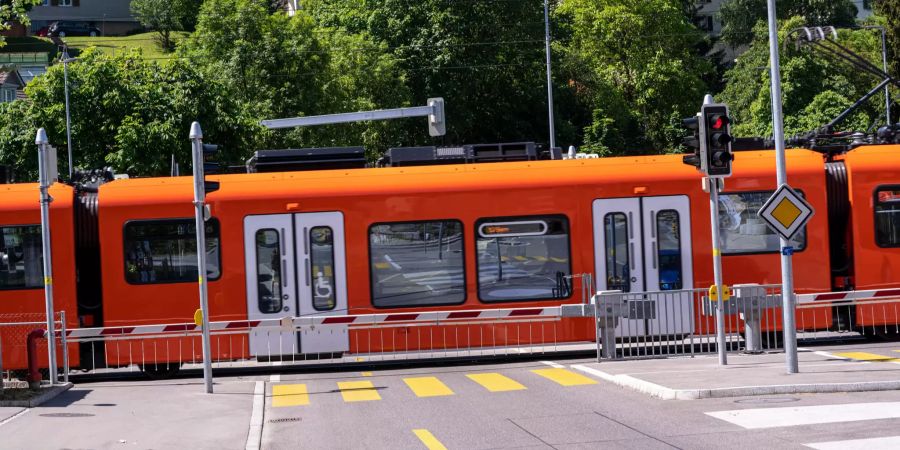 Bahnübergang mit geschlossener Schranke und RBS Zug beim RBS Bahnhof Ittigen.