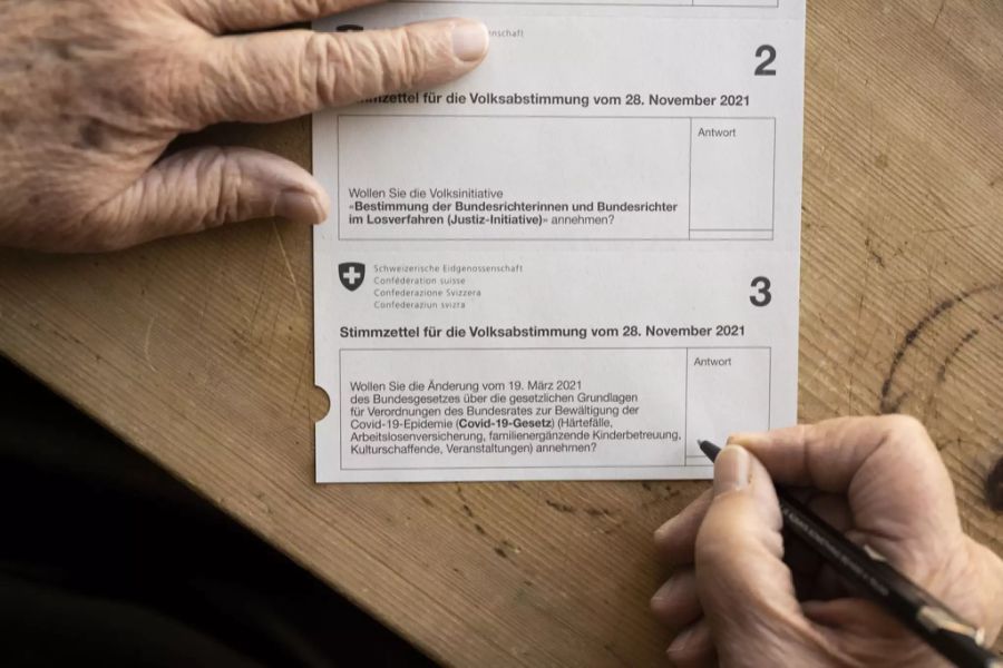 Eine Person füllt den Stimmzettel für die Volksabstimmung vom 28. November 2021 mit den Vorlagen der Pflegeinitiative (1), der Justiz-Initiatve (2) und des Covid-19-Gesetzes (3) aus, aufgenommen am 8. November 2021 in Zürich.