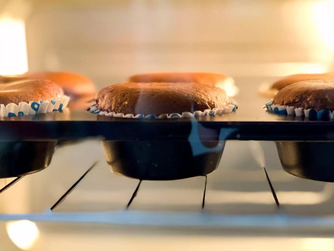 Zwischen dem Muffinteich und dem Backblech sind Papierförmchen. Muffins Backblech