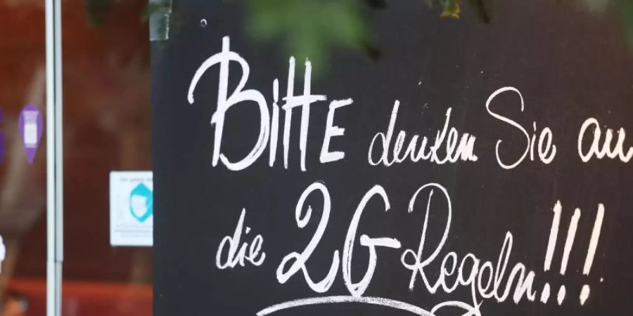 Ein Schild, das auf die 2G-Regeln hinweist, an einem Café in Bonn. Foto: Oliver Berg/dpa