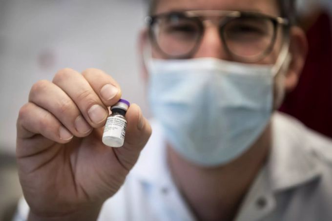 Ein Apotheker am Waadtländer Unispital CHUV hält ein Fläschchen des Impfstoffs Pfizer/Biontech vor die Kamera. Apotheke Waadt