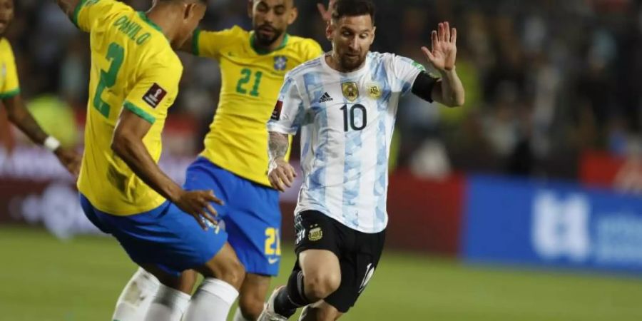 Lionel Messi (r) aus Argentinien in Aktion gegen Matheus Cunha (hinten) und Danilo (l) aus Brasilien. Foto: Gustavo Ortiz/dpa