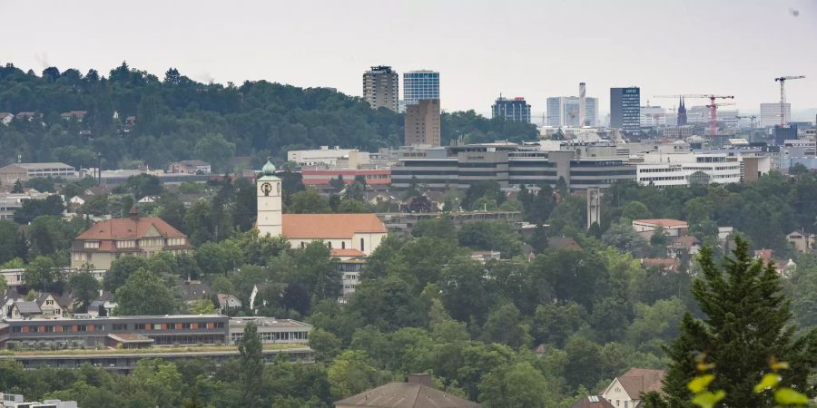 Blick auf die Industrie, das Schulhaus und die kath. Kirche St. Franz Xaver in Münchenstein.