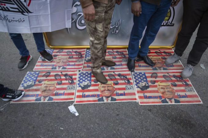 Trauernde treten über eine US-Flagge mit Bildern von Präsident Trump, während sie auf die Beerdigung von Irans Top-General Qassem Soleimani und Abu Mahdi al-Muhandis, stellvertretender Kommandeur der vom Iran unterstützten Milizen im Irak warten. irak konflikt