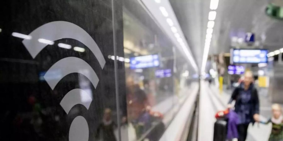 Ein WLAN-Logo auf der Fensterscheibe eines ICE weist darauf hin, dass in diesem Zug WLAN zur Verfügung steht. Foto: Christoph Soeder/dpa