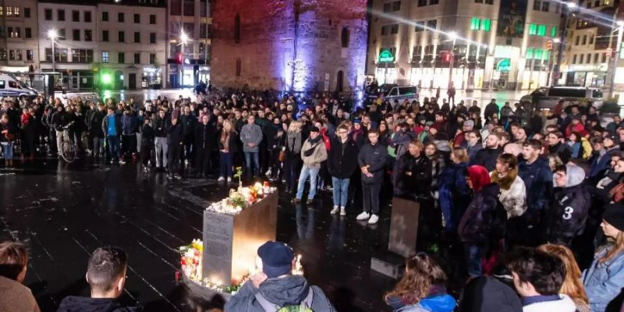 Trauernde stehen vor dem Roten Turm auf dem Marktplatz in Halle. Foto: Swen Pförtner/dpa