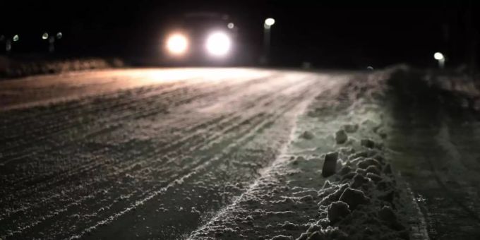 Ein Auto fährt am frühen Morgen über eine schneebedeckte Strasse. (Symbolbild) Schnee Schweiz wetter