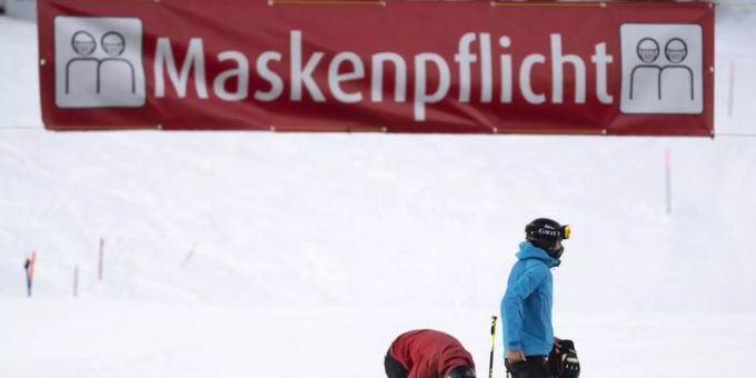 Zwei Skifahrer stehen unter einem Banner im Skigebiet Flumserberg, das auf die Maskenpflicht hinweist. Foto: Gian Ehrenzeller/KEYSTONE/dpa coronavirus