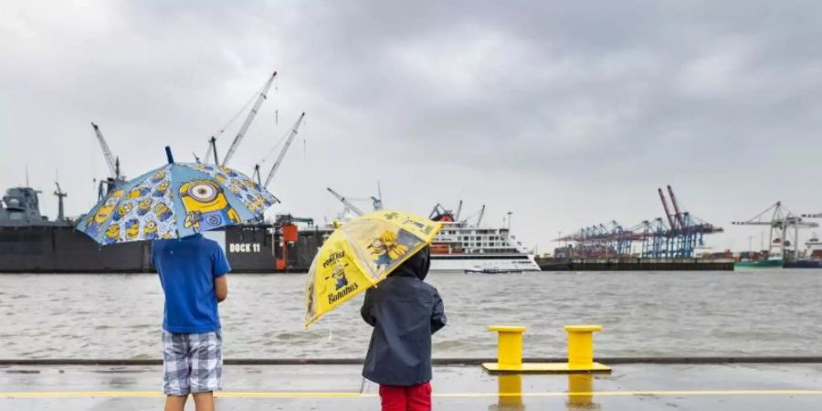 Mit bunten Regenschirmen schützten sich zwei Jungen im Hafen Hamburg vor dem Regen. Nach vielen trockenen, sonnigen Tagen regnet es wieder in der Hansestadt. Foto: Ulrich Perrey/dpa