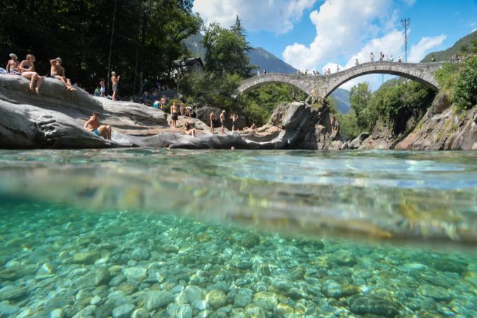 Ab jetzt nur noch mit Maske – Menschen geniessen das sonnige Wetter bei der «Ponte dei Salti», die über die Verzasca führt. Verzasca