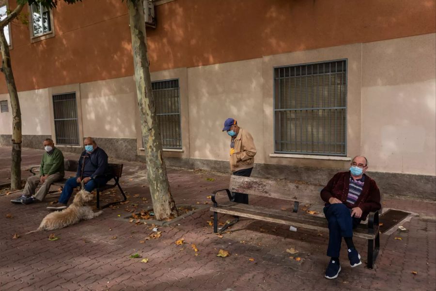 Ältere Menschen, die Mund-Nasen-Schutz tragen, um die Ausbreitung des Coronavirus zu verhindern, sitzen in einem Park in Vallecas, einem ärmeren Madrider Viertel, das teilweise abgeriegelt ist.