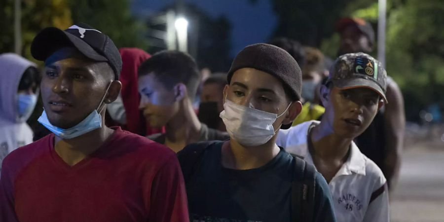 Migranten aus Honduras stehen nebeneinander und warten auf Hilfe auf ihrem Weg in Richtung USA. Foto: Moises Castillo/AP/dpa