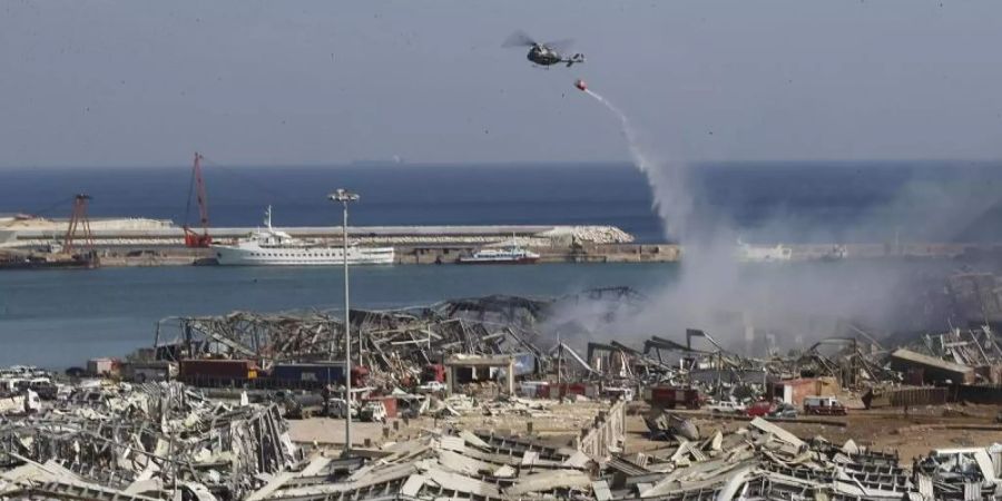 Ein Hubschrauber fliegt einen Löscheinsatz. Foto: Hussein Malla/AP/dpa